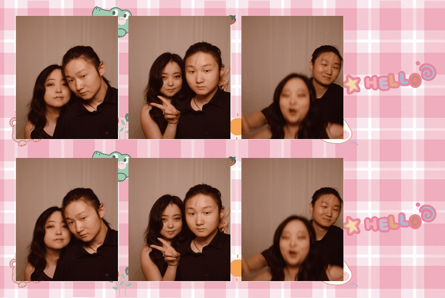 Four people posing in a photo booth with a pink checkered background, cartoon characters, and the word 'HELLO' in colorful letters. Some are making peace signs and playful expressions.